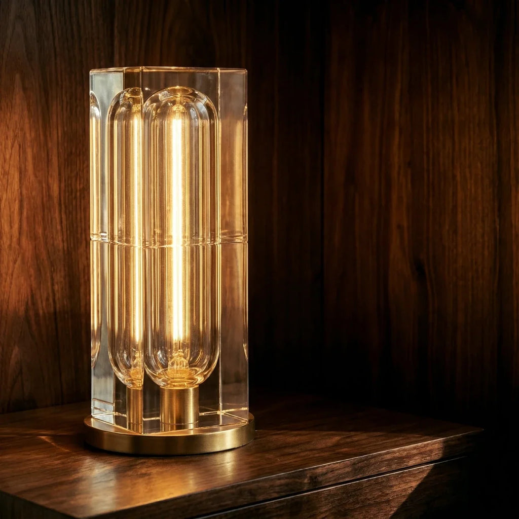 Close-up of the Clérachic tall crystal table lamp, a lit capsule bulb inside the clear block above a gold-tone round base.