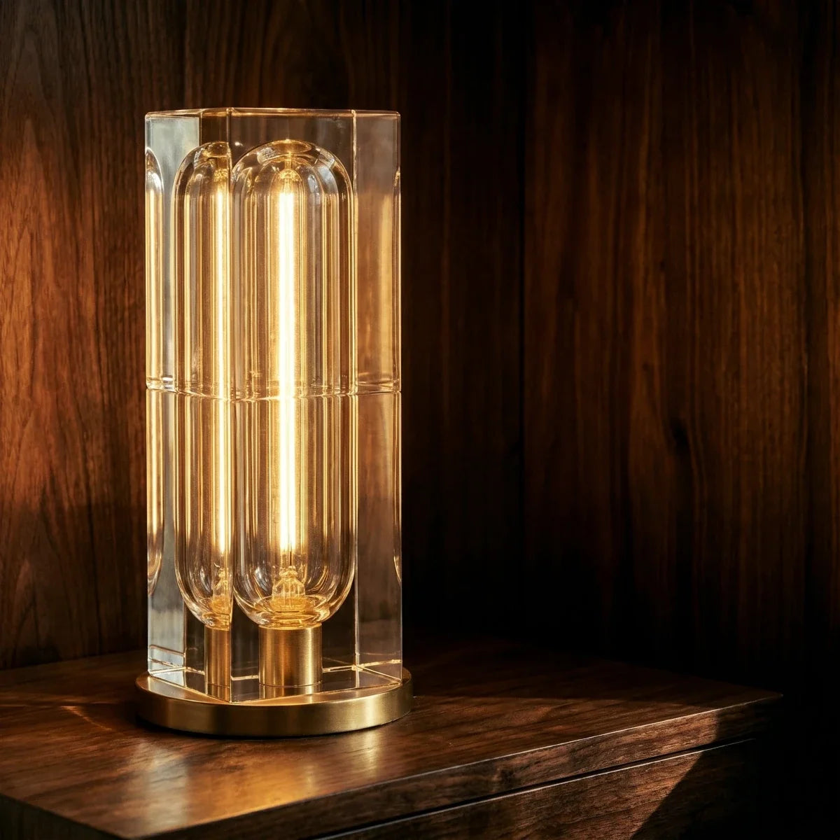 Close-up of the Clérachic tall crystal table lamp, a lit capsule bulb inside the clear block above a gold-tone round base.