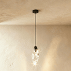 Clérachic single twisted clear glass pendant lit warm, with a black cap, cord and round canopy against limewash plaster.