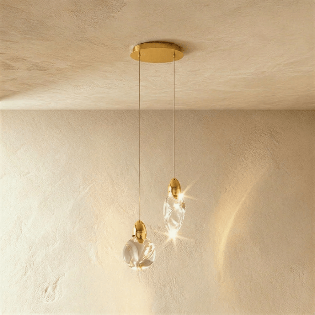 Clérachic pair of clear glass pendants, one round and one teardrop, on fine cords from a round brass canopy.