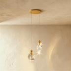 Clérachic pair of clear glass pendants, one round and one teardrop, on fine cords from a round brass canopy.