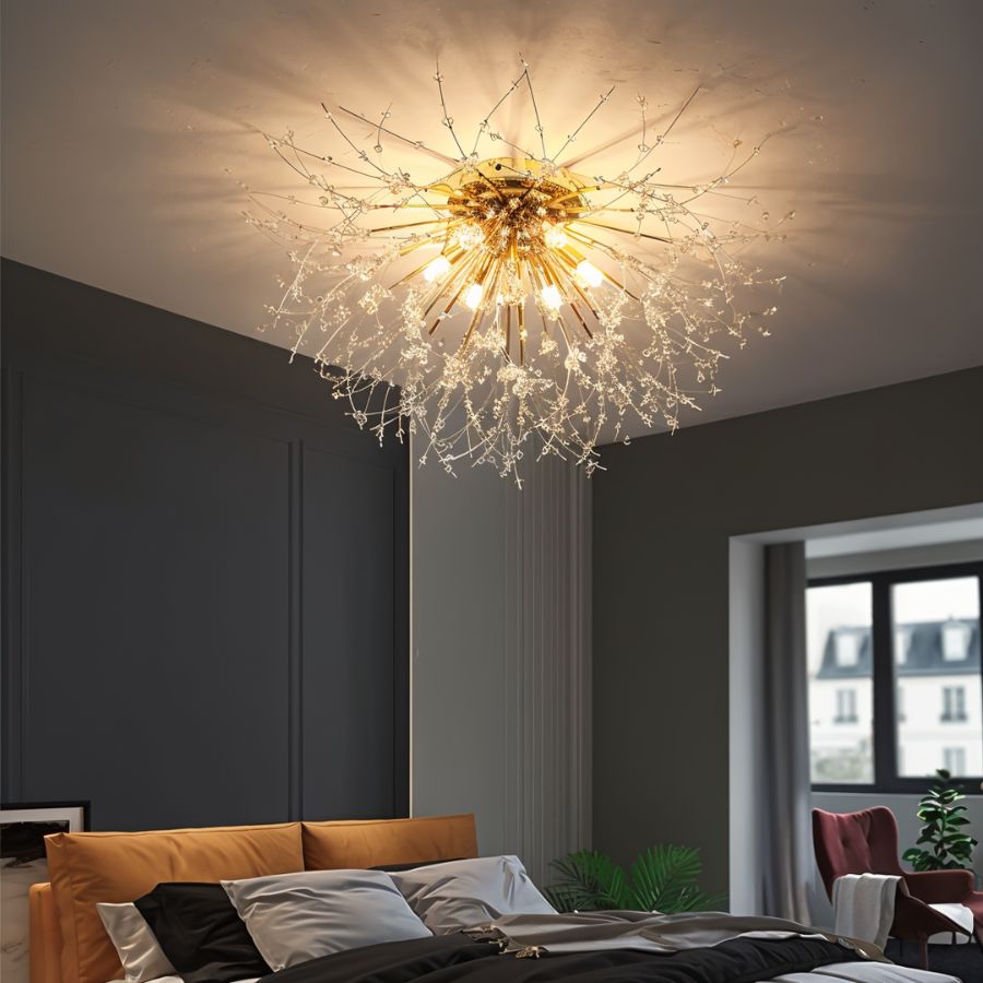Clérachic gold crystal flush ceiling light above a bed with tan headboard, a plant and a red armchair by a window.