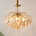 Lit Clérachic chandelier with amber teardrop crystals under a gold canopy, hung from a fabric-wrapped cord against a pale wall.