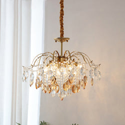 Amber and clear crystals catch the light on this Clérachic chandelier, hung beside sheer white curtains on a fabric-wrapped cord.