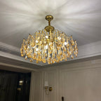 Clérachic chandelier switched on in a panelled room, throwing a soft starburst of light across the ceiling above a wall sconce.