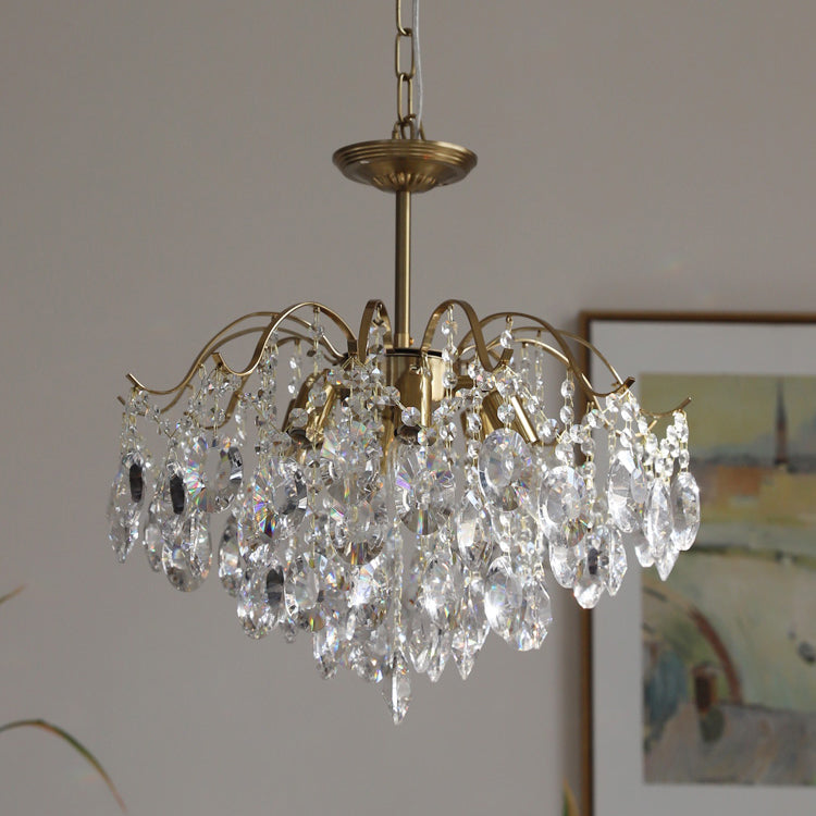Clear crystal version of this Clérachic chandelier hung from a chain, with a framed abstract painting behind it.
