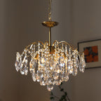 Clérachic gold chandelier with clear crystals and glowing bulbs, hung on a chain beside a framed print with orange tones.