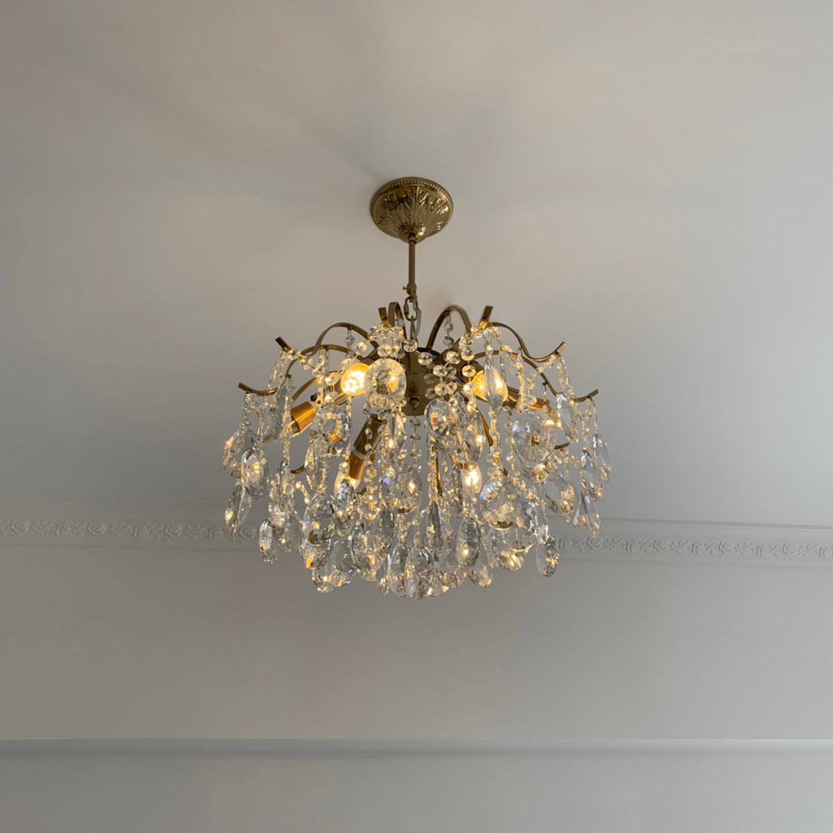 Clear crystals on a Clérachic chandelier fitted close to a pale ceiling, with a plain cornice line running behind it.