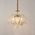 Lit Clérachic chandelier with amber and clear crystals, hung from a fabric-wrapped cord against a soft grey backdrop.