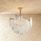 Clérachic unlit tiered crystal-rod chandelier with a gold canopy and twisted brass stem, shown on a limewash backdrop.
