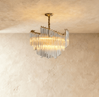 Clérachic compact tiered crystal-rod chandelier lit warm, hung from a gold canopy and twisted stem against limewash.