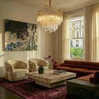 Clérachic crystal-rod chandelier in a bright sitting room with a travertine coffee table, boucle chairs and a rust velvet sofa.
