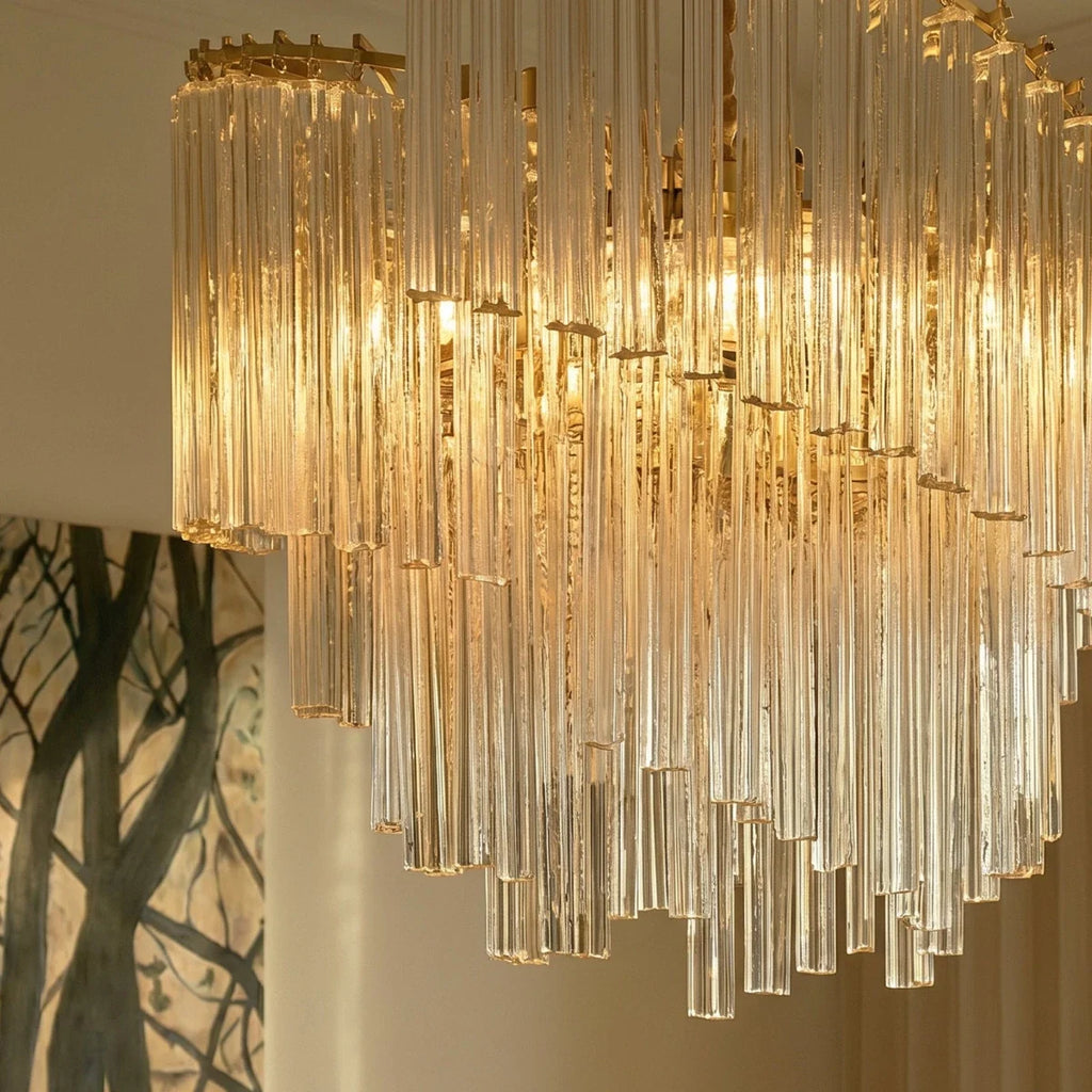 Clérachic close-up of fluted clear glass rods cascading in staggered lengths, lit from within by warm bulbs.