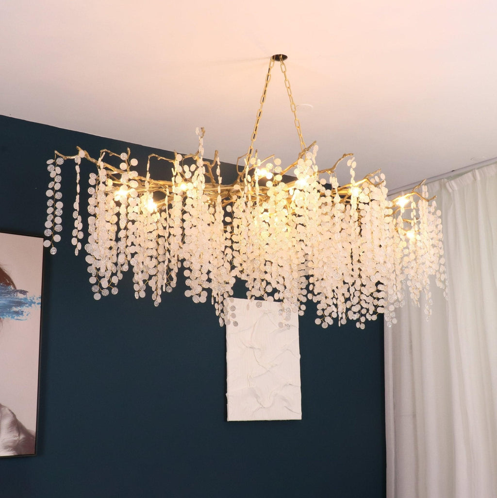 Clérachic branch chandelier glowing in a room with a deep teal wall, a textured white art panel and a long white curtain.