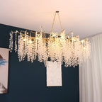 Clérachic branch chandelier glowing in a room with a deep teal wall, a textured white art panel and a long white curtain.