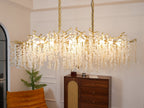 Clérachic chandelier lit above a walnut sideboard, its brass branches and hanging crystal discs spread wide on two chains.