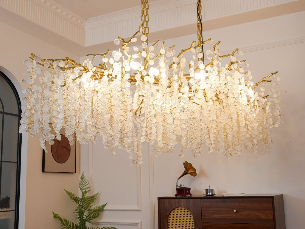 Close view from below of the lit Clérachic chandelier, with white cornice mouldings above and a record player on the sideboard.
