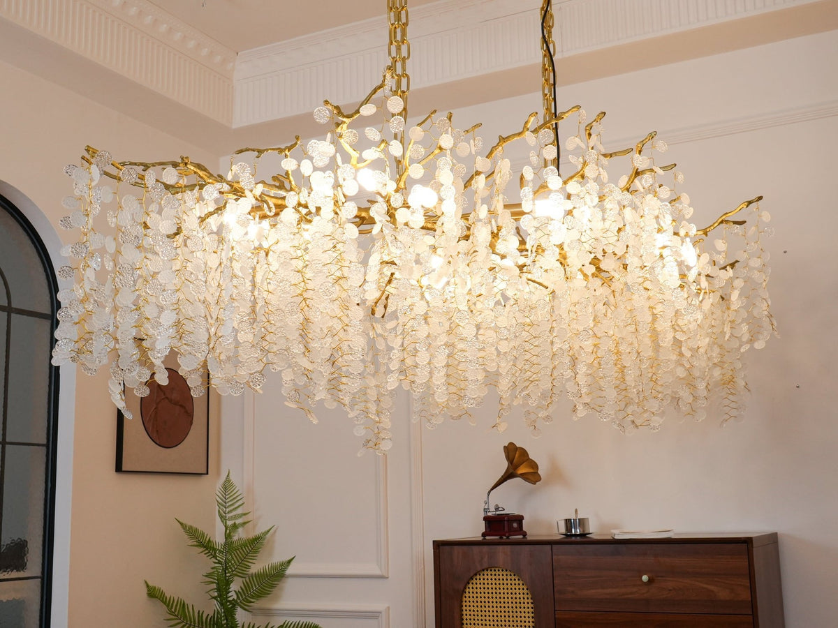 Close view from below of the lit Clérachic chandelier, with white cornice mouldings above and a record player on the sideboard.
