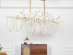 Unlit Clérachic chandelier in a white-panelled room, showing the brass branches and pale crystal discs above a walnut sideboard.