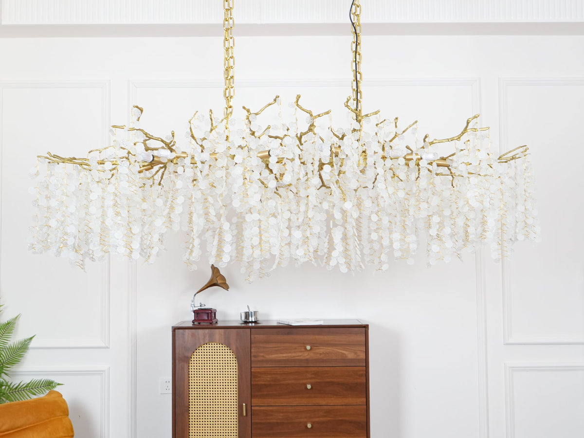 Clérachic branch chandelier switched off, its brass frame and trailing crystal strands hung above a sideboard with a record player.