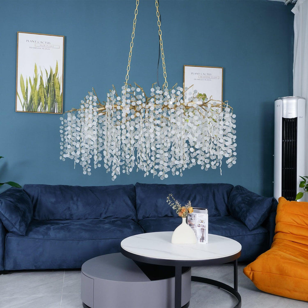 Clérachic chandelier hung above a navy velvet sofa and round white coffee tables, with a teal wall and an orange bean-bag chair.