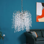 A smaller, drum-shaped Clérachic chandelier hung against a teal wall with an orange and red abstract print and a dark green sofa.