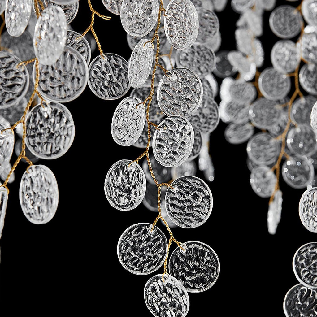 Close view of clear, hammered-texture glass discs on thin brass branches, part of this Clérachic chandelier, on black.