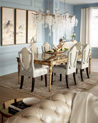 Lit Clérachic chandelier in a dining room with pale blue panelled walls, framed landscape prints and a carved gilt table.
