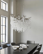 Clérachic chandelier in a bright room with tall black-framed windows, above a dark table with small silver bowls.