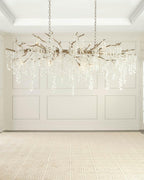 Clérachic chandelier hung in an empty, white-panelled room with a pale rug, shown evenly lit from within.