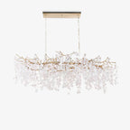Clérachic long chandelier on a white backdrop, hung from a slim canopy plate, with a brass branch frame and pale crystal discs.