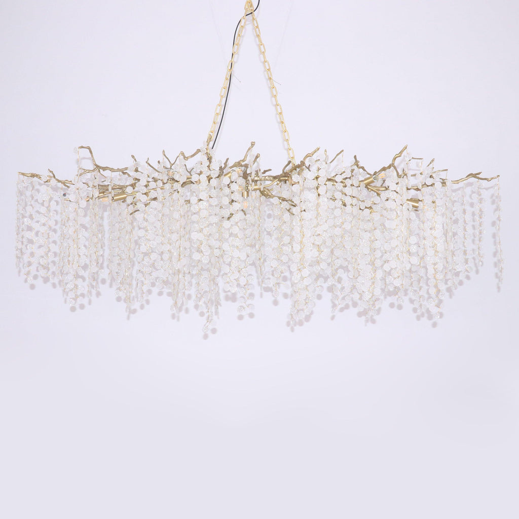 Clérachic brass branch chandelier on a soft lilac-grey backdrop, hung from a chain with crystal discs falling in straight strands.