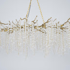Close view of the brass branches and chain on this Clérachic chandelier, with frosted crystal strands on a pale blue-grey backdrop.