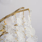 Close view of a brass branch with textured glass discs tied on with fine gold wire, from this Clérachic chandelier.