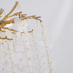 Close view of the hanging strands of frosted discs on this Clérachic chandelier, with a lit bulb at the branch top on the left.