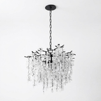 A round Clérachic chandelier in black with a black chain and canopy, on a pale grey backdrop.