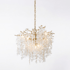Lit round Clérachic chandelier in brass, with a gold chain and warm glowing bulbs among the frosted crystal discs.
