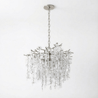 A round Clérachic chandelier with a nickel finish, a chain and a round ceiling plate, on a white backdrop.