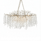 Long Clérachic chandelier with a nickel finish and a pale chain, with warm bulbs glowing among the crystal discs.