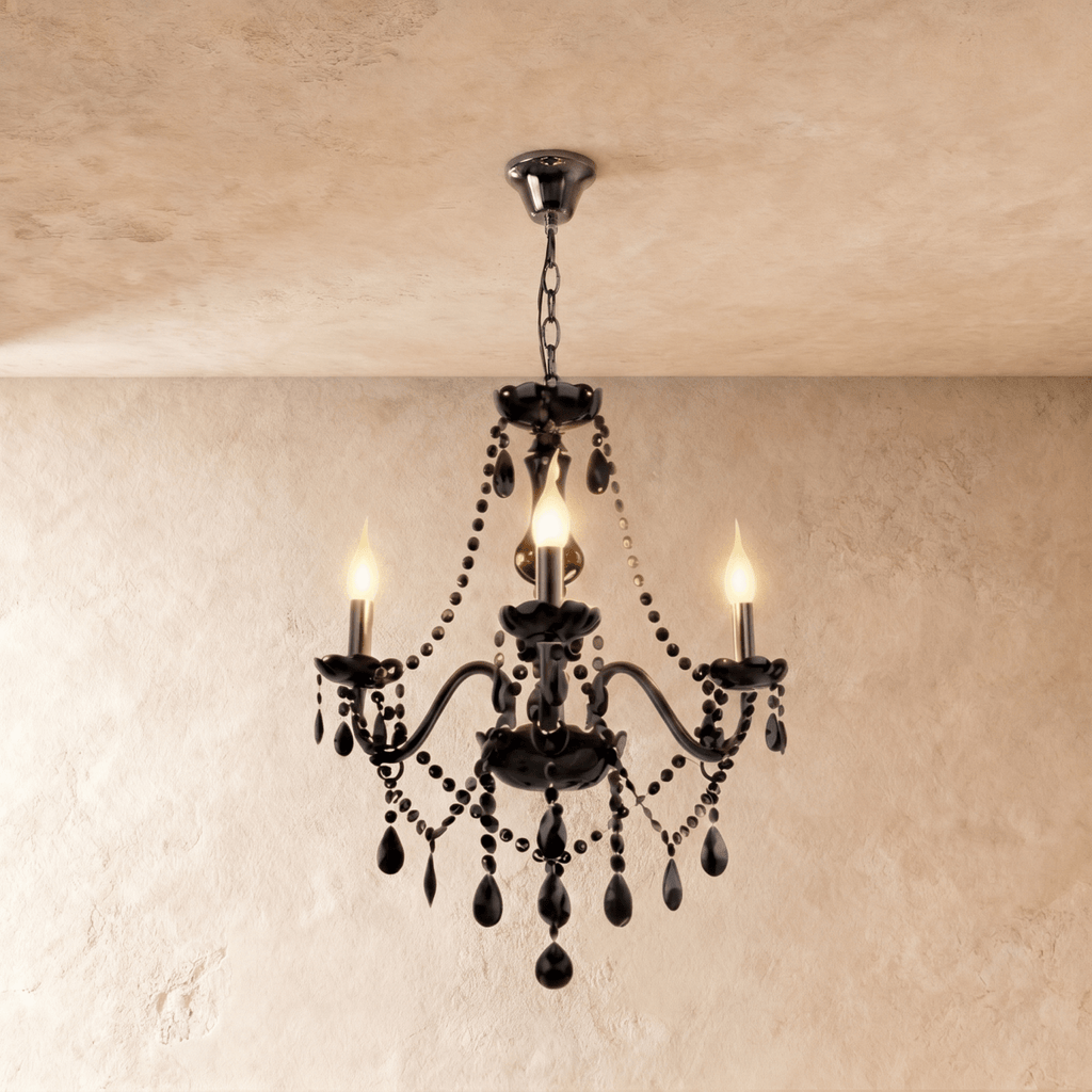 Clérachic chandelier in black glass hangs from a fine chain, three candle bulbs lit against a cream plaster wall.