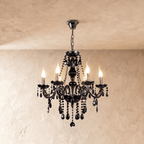 A studio view of the Clérachic chandelier's six black glass arms, lit candle bulbs and beaded crystal chains on show.