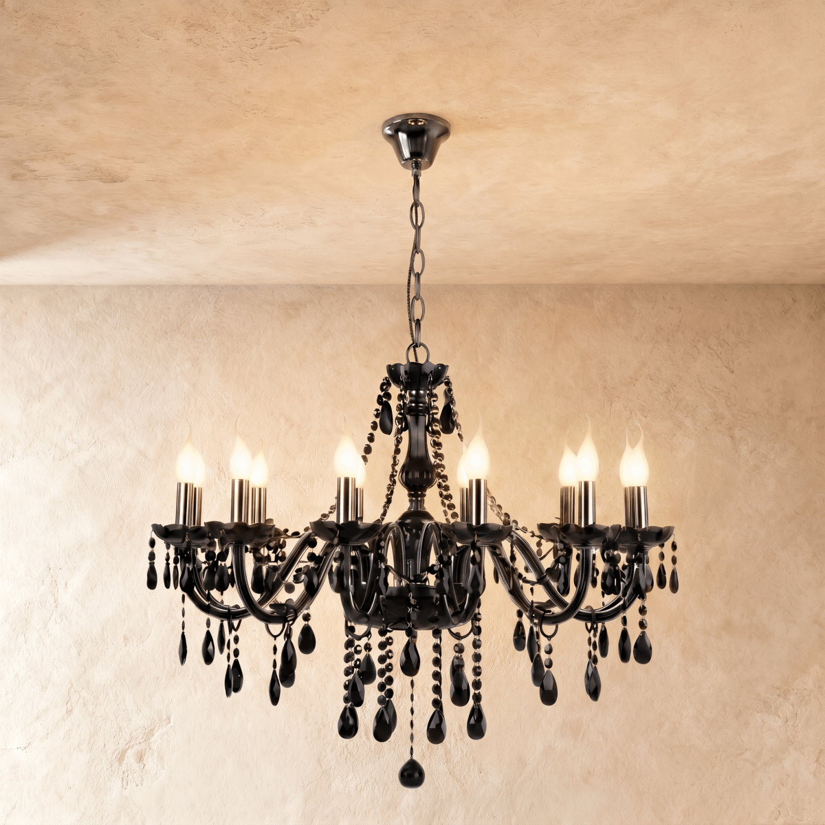 Clérachic chandelier with eight black glass candle arms, lit bulbs and dense faceted crystal drops on a plaster wall.