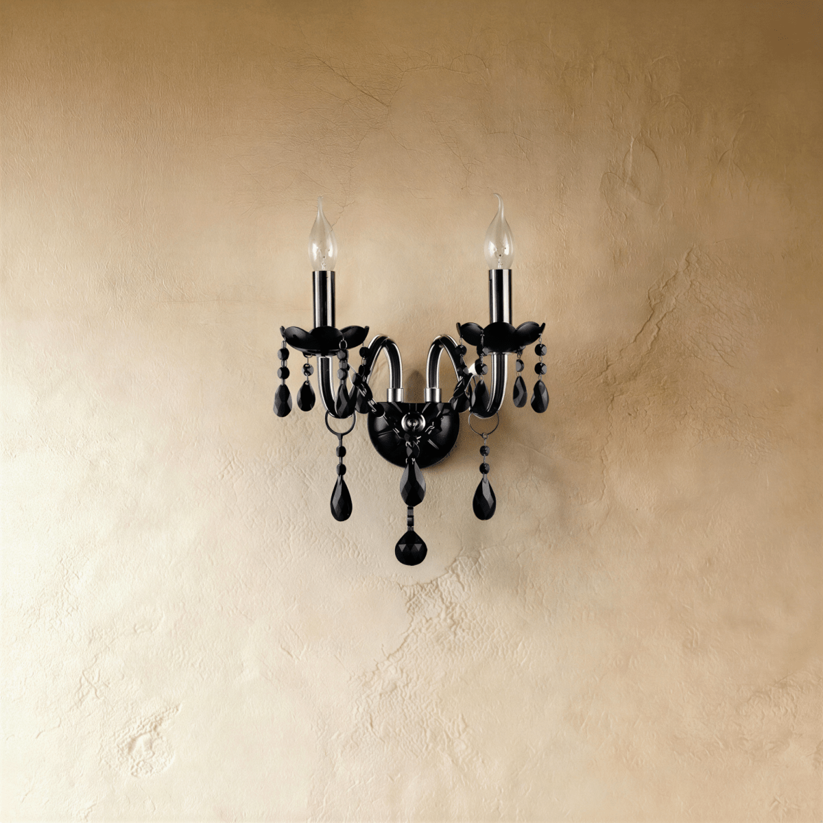A close front view of the Clérachic wall light's black glass arms, lit candle bulbs and hanging crystal beads.