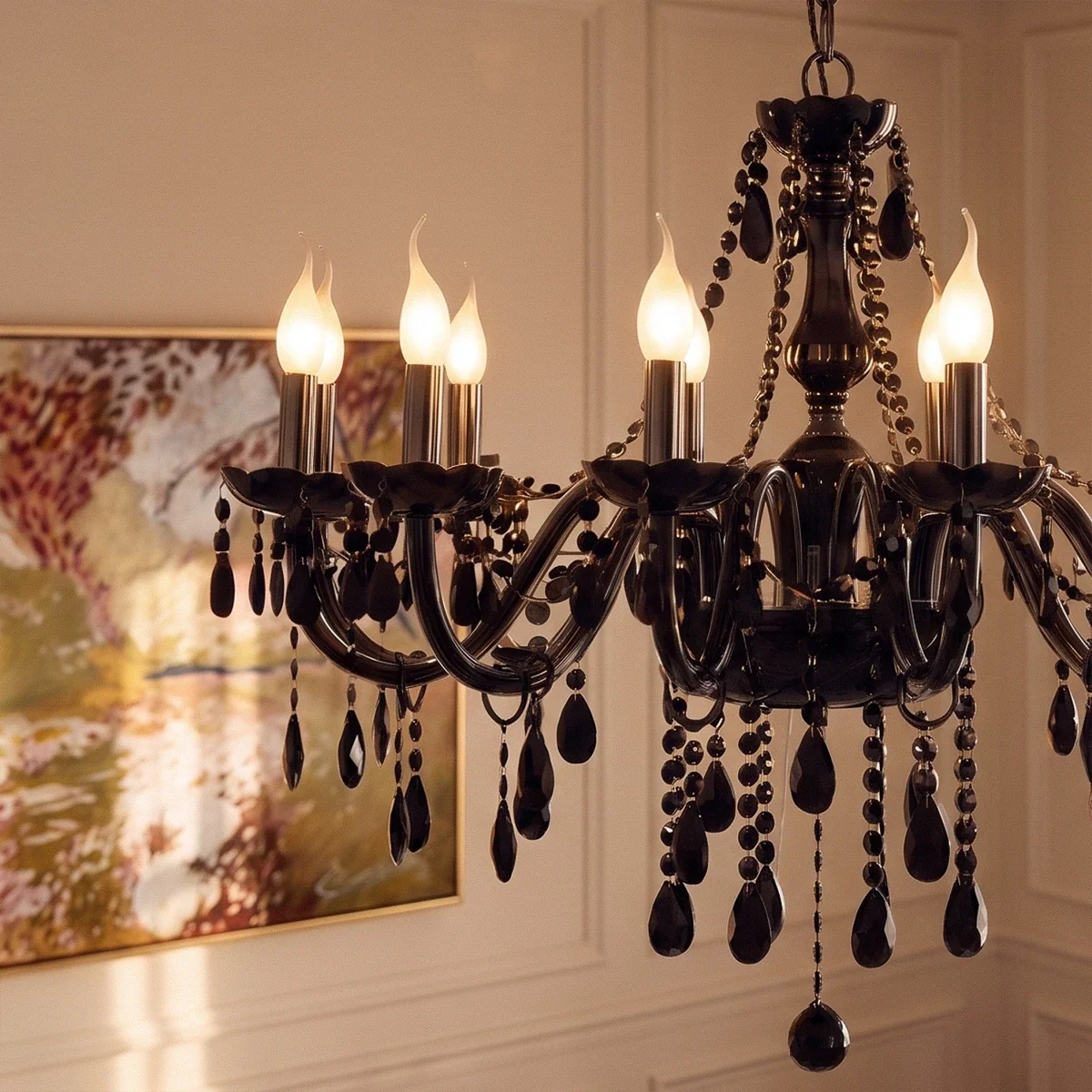 A close view of the Clérachic chandelier's lit candle arms and black glass crystal drops, a painting soft behind.