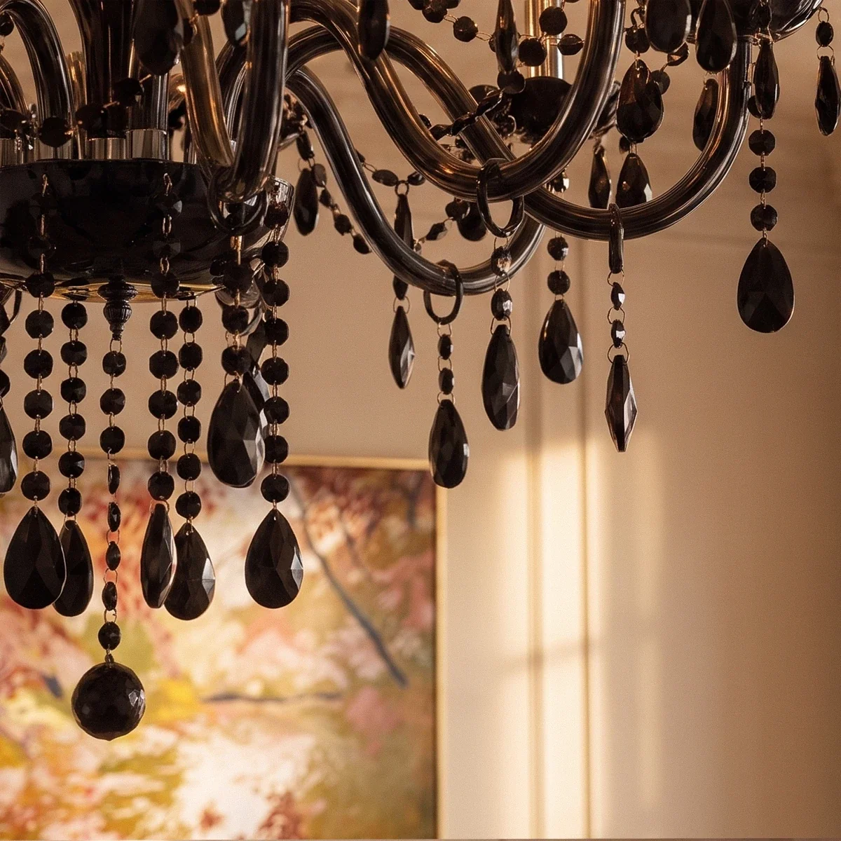 Faceted black crystal drops cascade from the Clérachic chandelier's curved glass arms, a framed painting glowing behind.