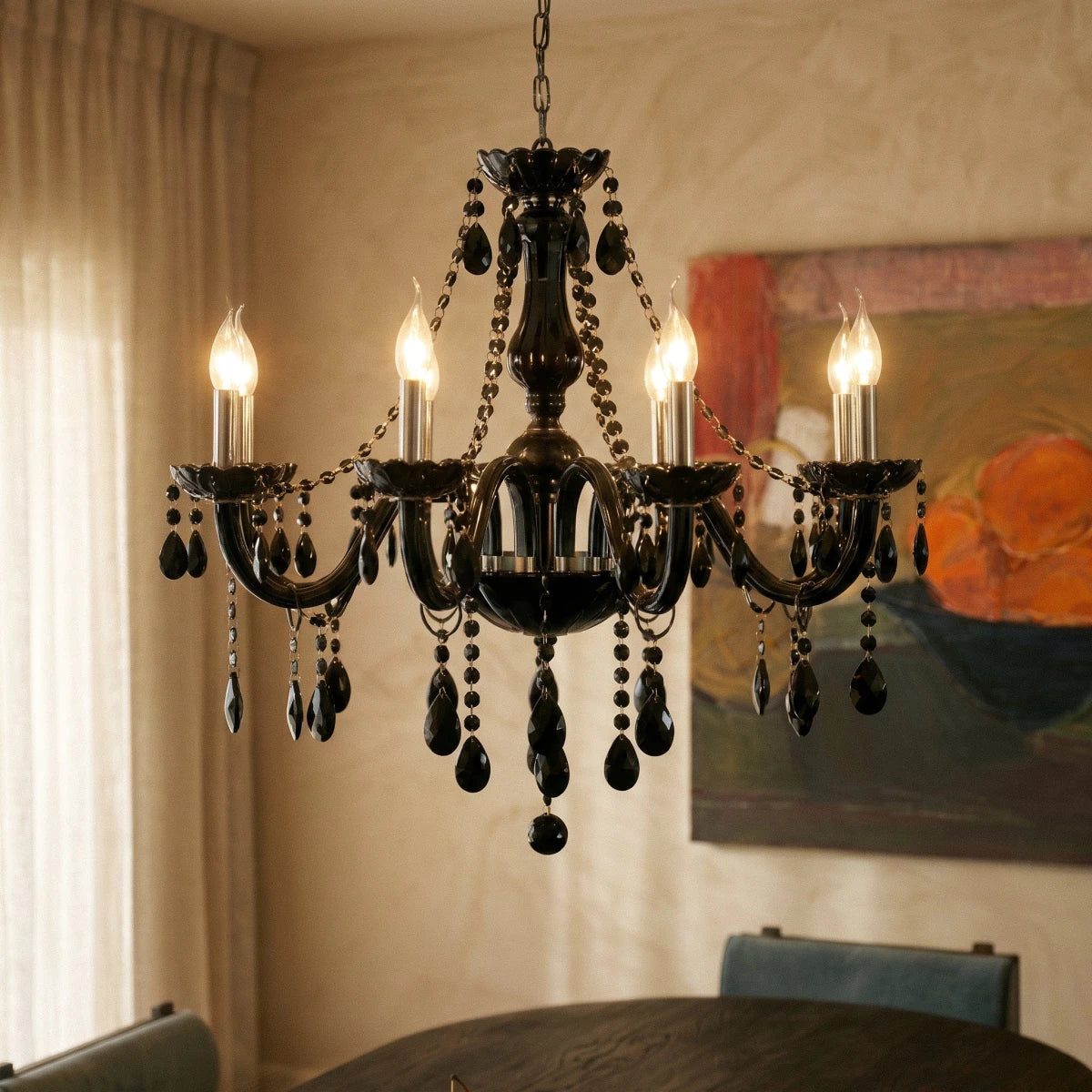 A closer view of the Clérachic chandelier's black glass arms lit above a dark dining table, an abstract painting behind.