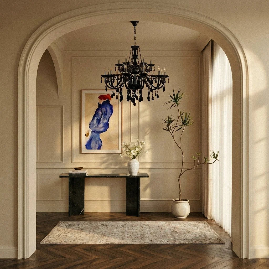 A large tiered Clérachic chandelier in black glass hangs in an arched entryway, above a marble console and framed portrait.