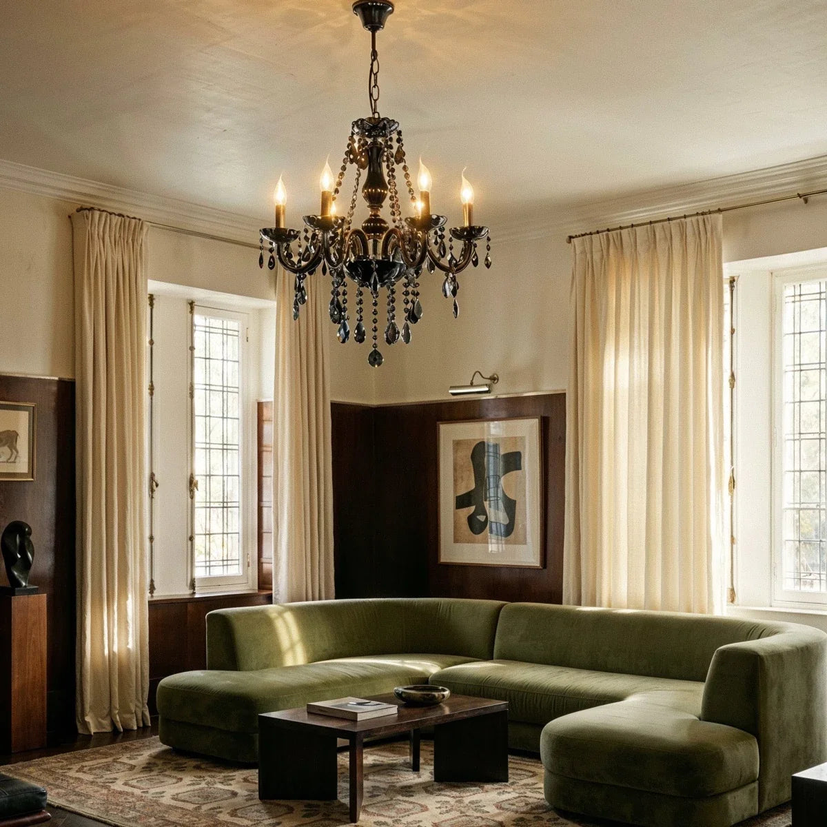 A Clérachic chandelier in black glass lights a living room with a green velvet sectional sofa and wood-panelled walls.
