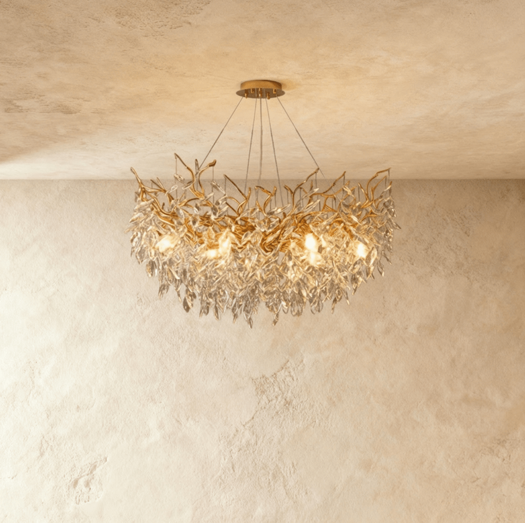 Clérachic crystal chandelier lit warm, its gold branches thick with cut crystal leaves beneath a round ceiling plate.