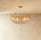 Clérachic crystal chandelier lit warm, its gold branches thick with cut crystal leaves beneath a round ceiling plate.